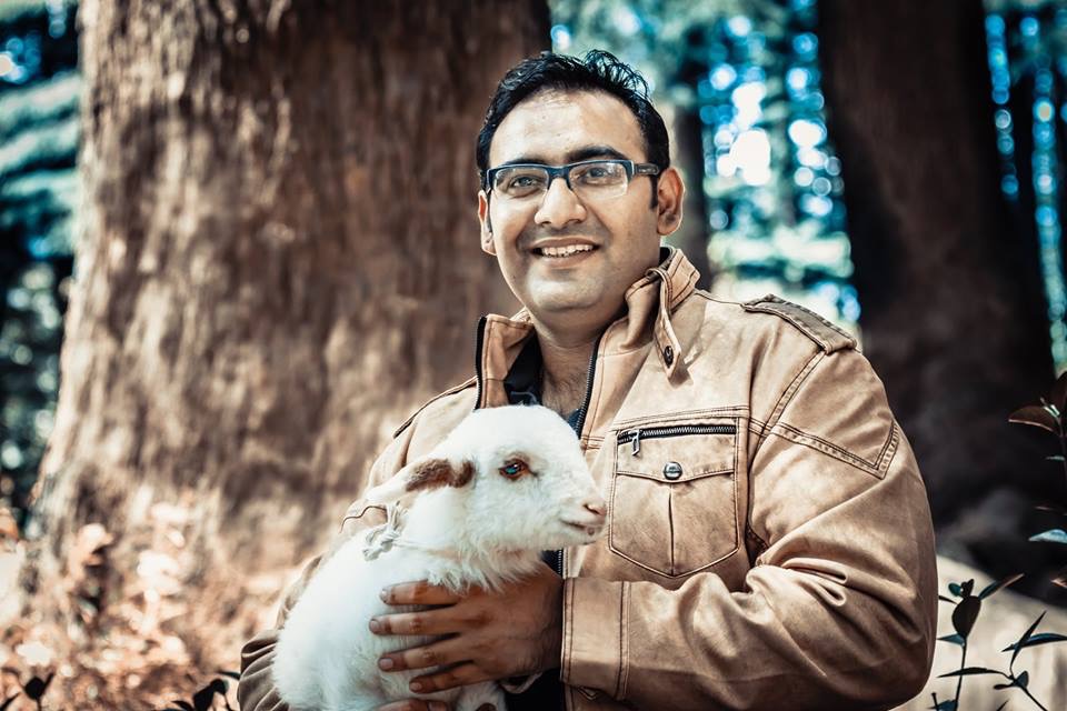 Prakhar holding a baby goat in the forest